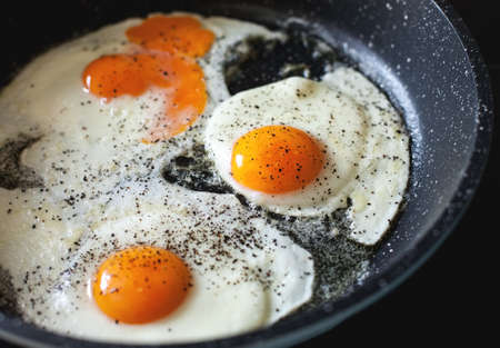 Fried eggs with black pepper in a frying panの写真素材