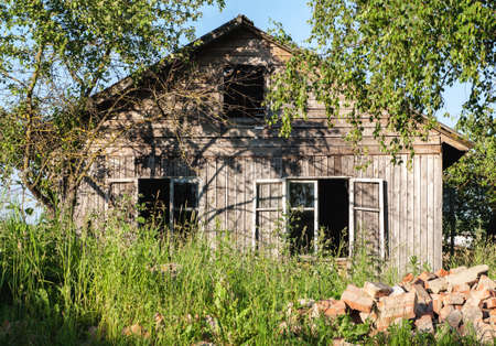 Old abandoned wooden house among green treesの写真素材