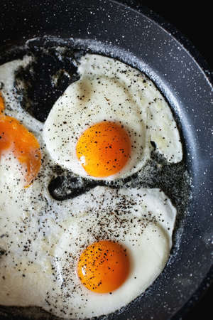 Fried eggs with black pepper in a frying pan, verticalの写真素材