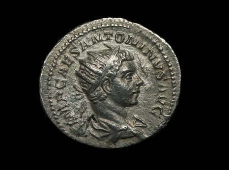 Ancient silver roman coin isolated on black, close-up shotの写真素材