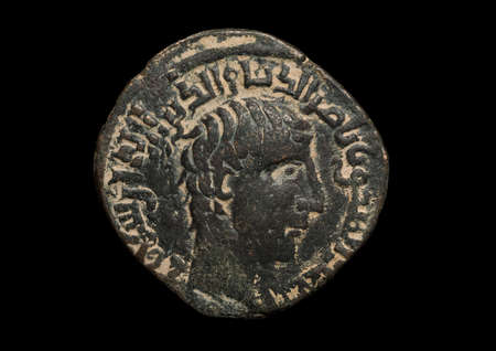 Ancient bronze islamic coin with portrait isolated on black, close-up shotの写真素材