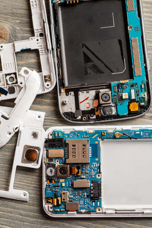 Parts of disassembled digital gadgets on wooden table, selective focus, overhead view, vertical shot, service and repait conceptの写真素材
