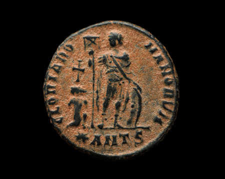 Ancient roman copper coin with person image on it isolated on black, close-up shotの写真素材