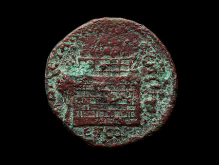 Ancient bronze roman coin isolated on black, close-up shotの写真素材