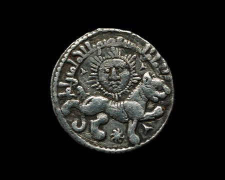 Ancient Seljuk silver coin with image of sun and lion isolated on black, close-up shotの写真素材