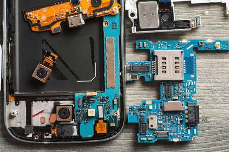 Parts of disassembled digital gadgets on wooden table, selective focus, overhead view