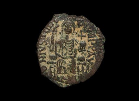 Ancient copper Byzantine copper coin with figure on it isolated on black, close-up shotの写真素材