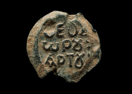 Round antique post seal with greek letters on it, isolated on black, close-up shotの写真素材