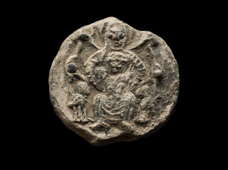 Antique post seal with image of saint on it, isolated on blackの写真素材