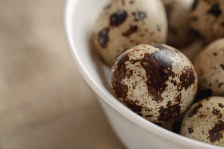 Quail eggs in a white ceramic bowl, close-up shot