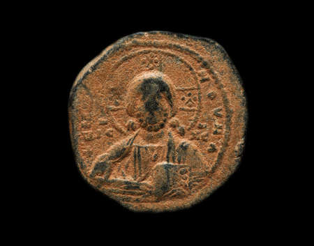 Ancient copper coin with saint figure on it, close-up shot, isolated on blackの写真素材