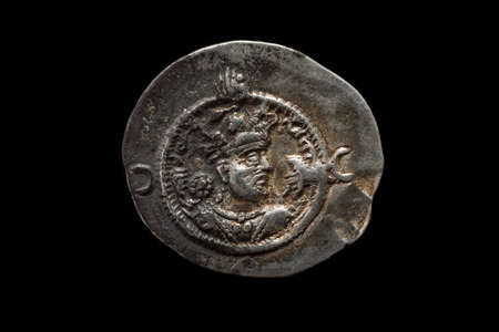 Ancient silver Sassanian coin with emperor portrait, isolated on black, macro shotの写真素材