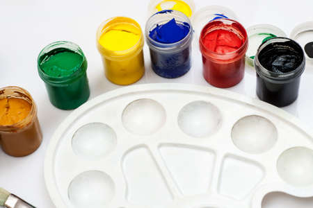 Open gouache jars with empty white plastic palette on a white background.の写真素材