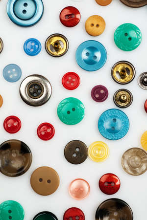 Close-up shot of many different buttons on a white background, flat lay pattern, vertical