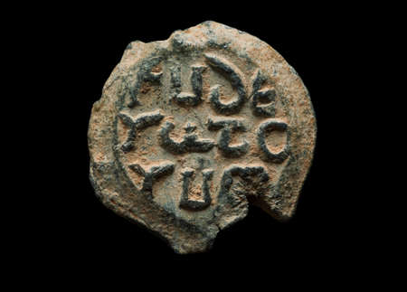 Antique post seal made of lead with greek letters on it, isolated on black, close-up shotの写真素材