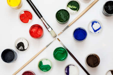 Gouache jars with paintbrushes in the middle on a white background, closeup shotの写真素材