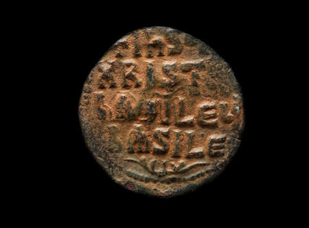 Ancient coin made of copper with religious text on it, close-up shot, isolated on blackの写真素材