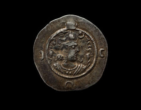 Ancient silver Sassanian coin with ruler portrait on it isolated on black, closeup shotの写真素材