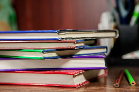 Stack of colored books with stationery stuff on wooden table, selective focusの写真素材