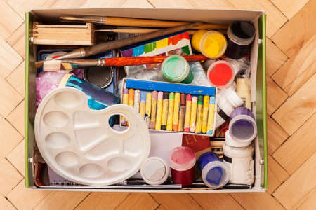 Crayons, gouache, paint brushes, pallet and other drawing stuff folded in box, top view.の写真素材