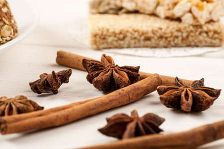 Cinnamon sticks with star anise on a white wooden table with sweet dessert on it.の写真素材
