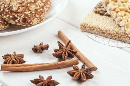 Cinnamon sticks with star anise on a white wooden table with sweet dessert on it.の写真素材