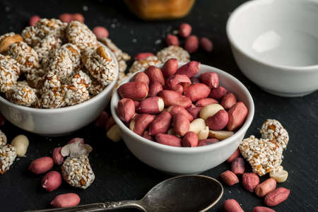 Different peanuts in ceramic bowls on a wooden table.の写真素材