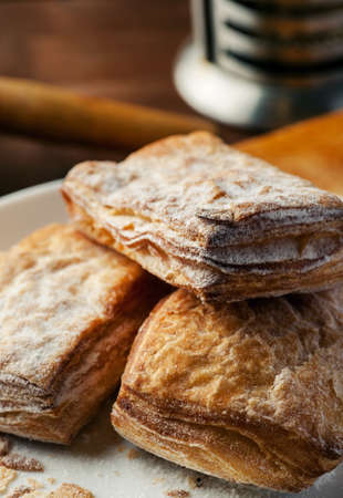 Puff pastry cookies in a white plate on a wooden table, selective focus, vertical.の写真素材