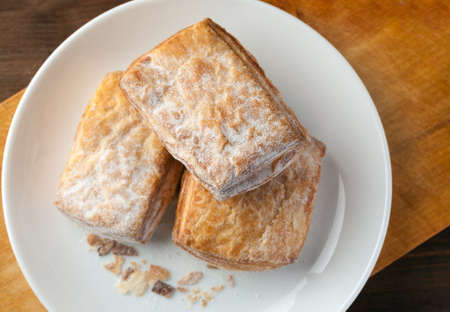 bakery in a white ceramic plate on a wooden board, top view.