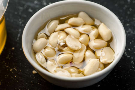 Raw peanuts in a white bowl filled with honey.