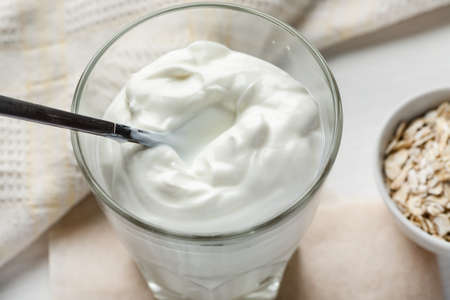 Full glass of yogurt with metal spoon in it.の写真素材