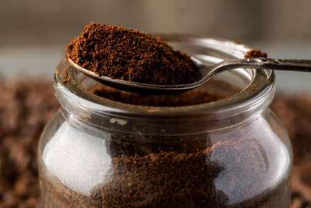 Ground coffee in metal spoon on a glass jar.の写真素材
