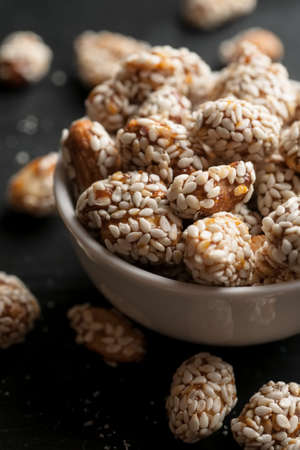 Roasted peanuts covered with sesame in white ceramic bowl, vertical.の写真素材