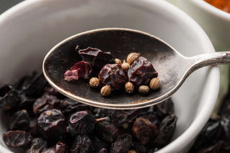 Dry barberry berries with coriander seeds in metal spoon macro shot.の写真素材