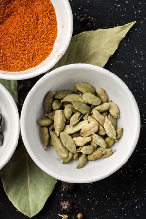 Different condiments in white bowls on a black wooden table, top view, vertical.の写真素材