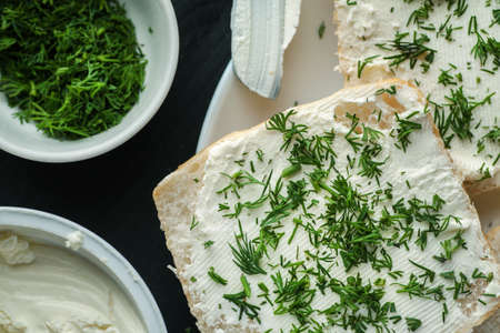 White bread slices covered with curd cheese and sprinkled with fresh dill, top view, closeup shot.の写真素材