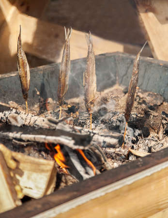 Fresh fish smoking over hot coals, vertical, selective focus