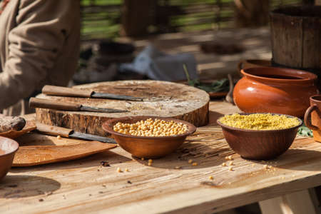 Chickpea and millet in the ceramic bowls on a wooden table among other kitchen utensilsの写真素材