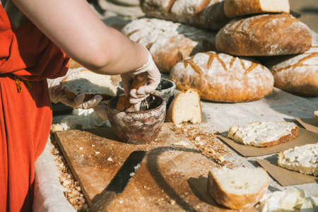A lot of big round loafs of wholegrain bread on a wooden table with hands making sandwichesの写真素材