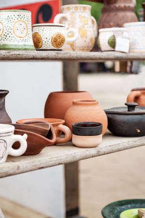 Different handemade pottery on a wooden shelf, vertical