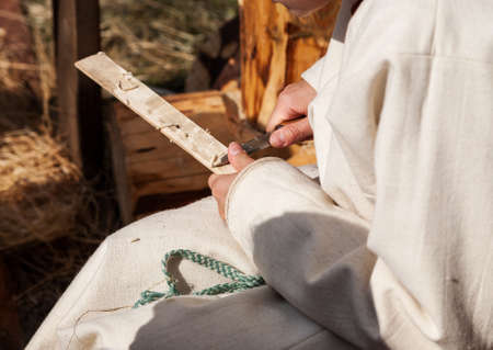 Carpenter working with wooden plank with sharp knifeの写真素材