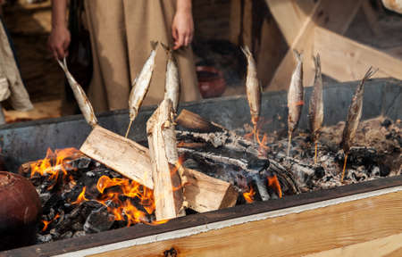Fish smoking over hot coals, open fire outdoors cookingの写真素材