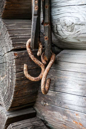 Two metal rusted hooks hanged on old gray log wall, verticalの写真素材