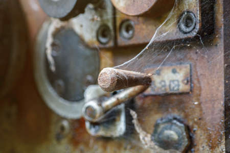 Rusted control elements of old industrial machine covered with spider webの写真素材