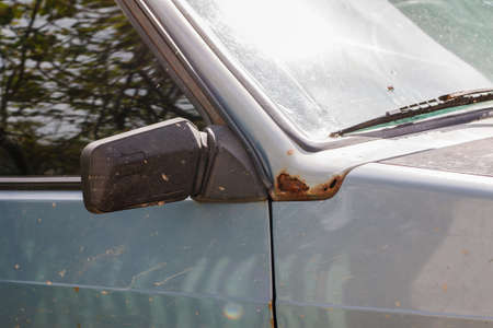 Fragment of an old car with rusted parts of body