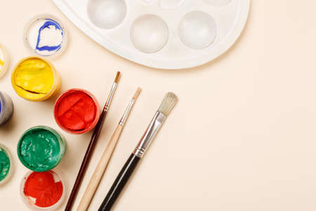 Paintbrushes, open paint jars and palette on a table, top view, copy spaceの写真素材