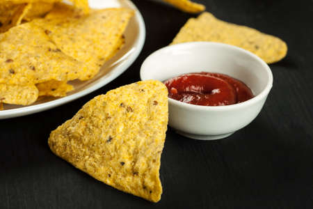 Nachos chips with sauce on a black tableの写真素材