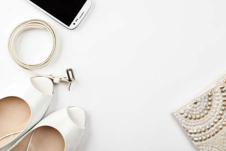 Female white shoes, belt, smartphone and bag on a white background top view, flat layの写真素材