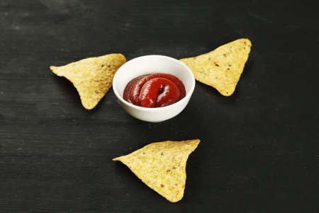 Corn chips nachos with sauce on a black tableの写真素材