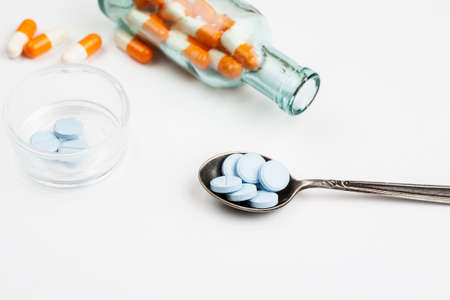 Medications and pills with spoon and syringe on a white backgroundの写真素材